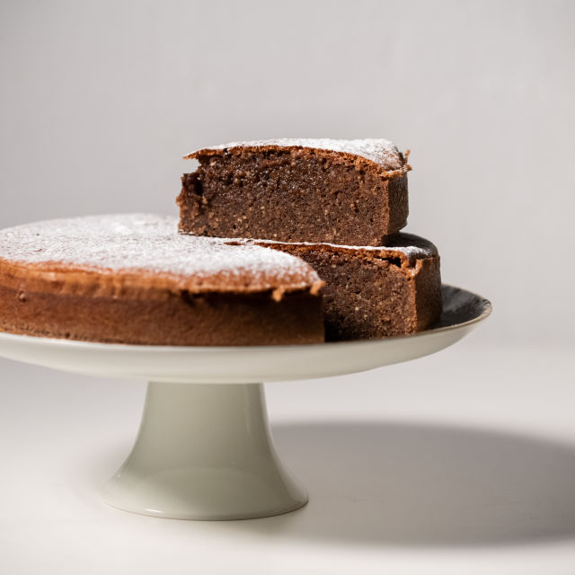 Bolo de queijo de brownie caseiro em chapa branca, decorado com morangos,  mirtilo e cereja, no jogo americano estilo inglês, na mesa de madeira.  usado para decorar a loja.